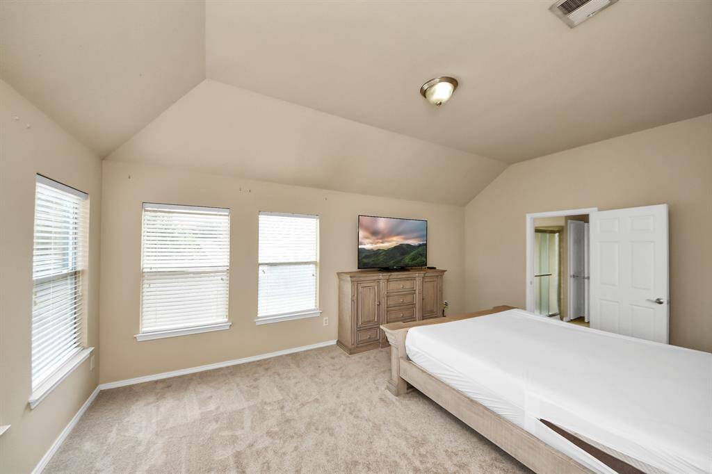 Spacious and serene, this carpeted primary bedroom features multiple oversized windows that let in sunlight. A restful space designed for comfort and calm.