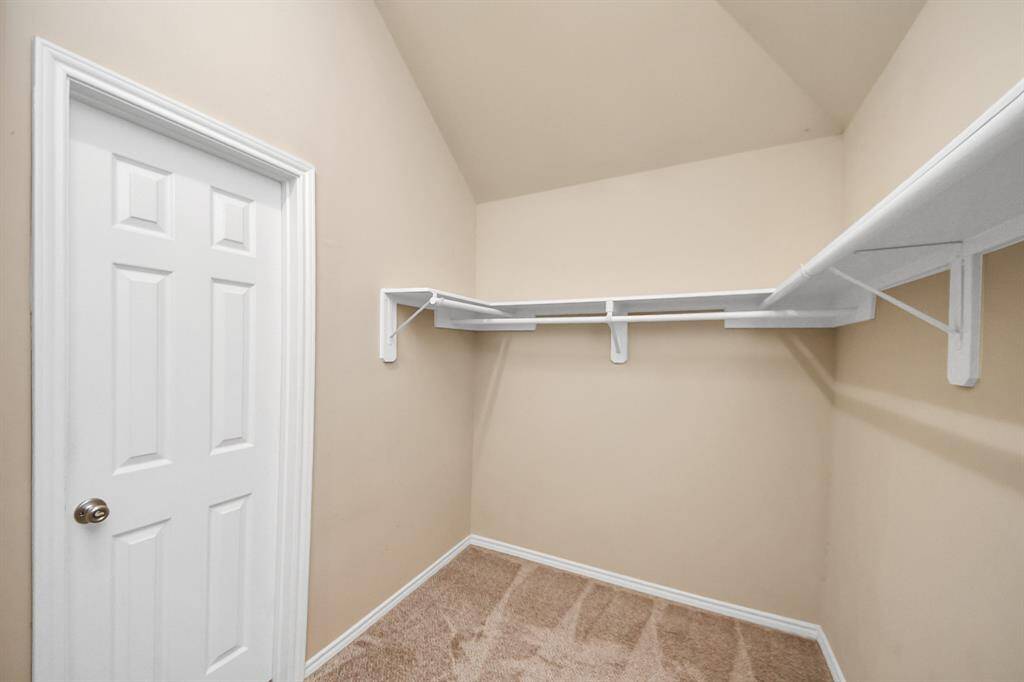 A full-entry closet offers functionality with built-in hanging rods and overhead racks. Carpeting underfoot adds a soft touch to the space.
