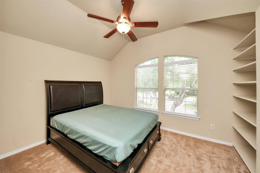 Charming and versatile, this secondary bedroom showcases built-in shelving and arched windows that adds architectural interest. A ceiling fan provides year-round comfort.
