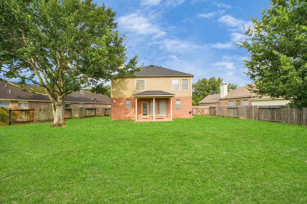 The rear elevation reveals a covered patio that extends from the back of the home—an inviting spot to relax while overlooking the expansive, lush yard.