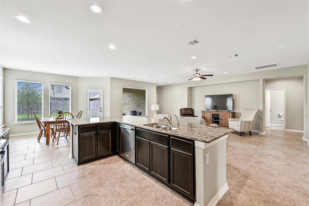 Enjoy the seamless flow from the kitchen into the breakfast room and living area, all bathed in natural light from a wall of windows overlooking the backyard—perfect for both casual dining and entertaining.