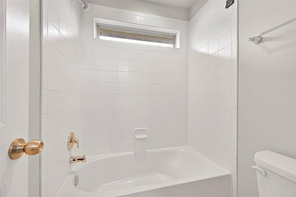 Freshly painted Jack & Jill style bathroom with a spacious vanity, private tub/shower combo, and access from two secondary bedrooms.