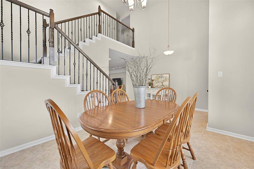 An alternate view of the dining room highlights its open connection to the entryway and main living space, complemented by the elegant wrought iron stair railing and neutral tile flooring that continues throughout the first floor.