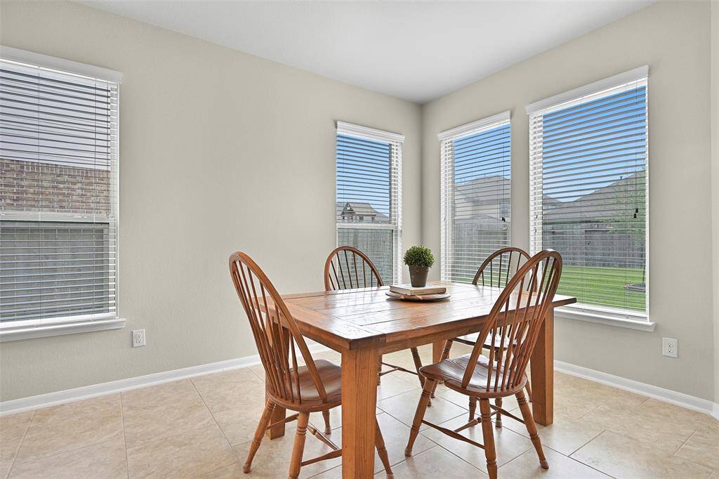 A bright and airy breakfast nook sits just off the kitchen, surrounded by a wall of windows that overlook the backyard and fill the space with natural light.