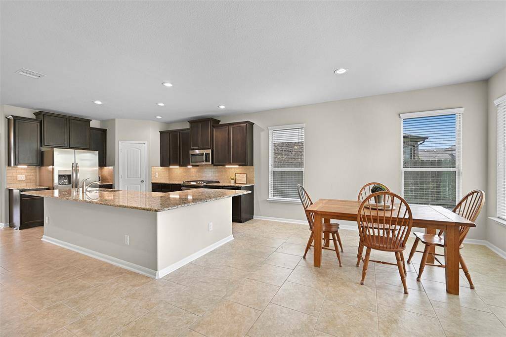 The spacious breakfast room offers a seamless flow from the kitchen and living areas, creating the perfect spot for casual dining with backyard views and abundant natural light.