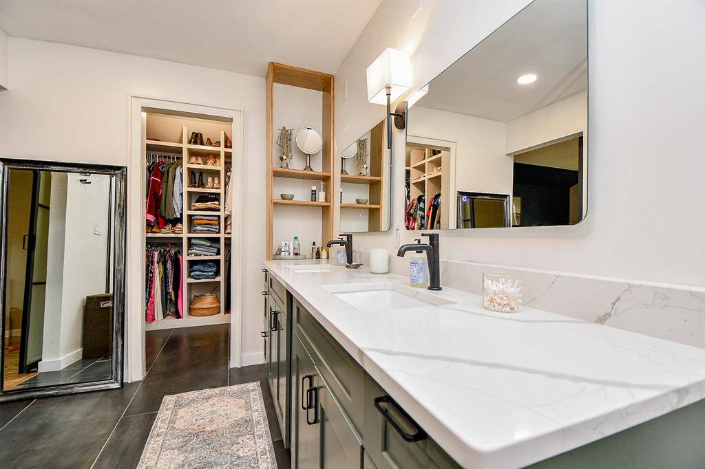This photo showcases a modern bathroom with dual sinks, sleek fixtures, and a large mirror. Adjacent is a spacious walk-in closet with ample shelving and storage space. The design is clean and stylish, ideal for a homebuyer seeking convenience and elegance.