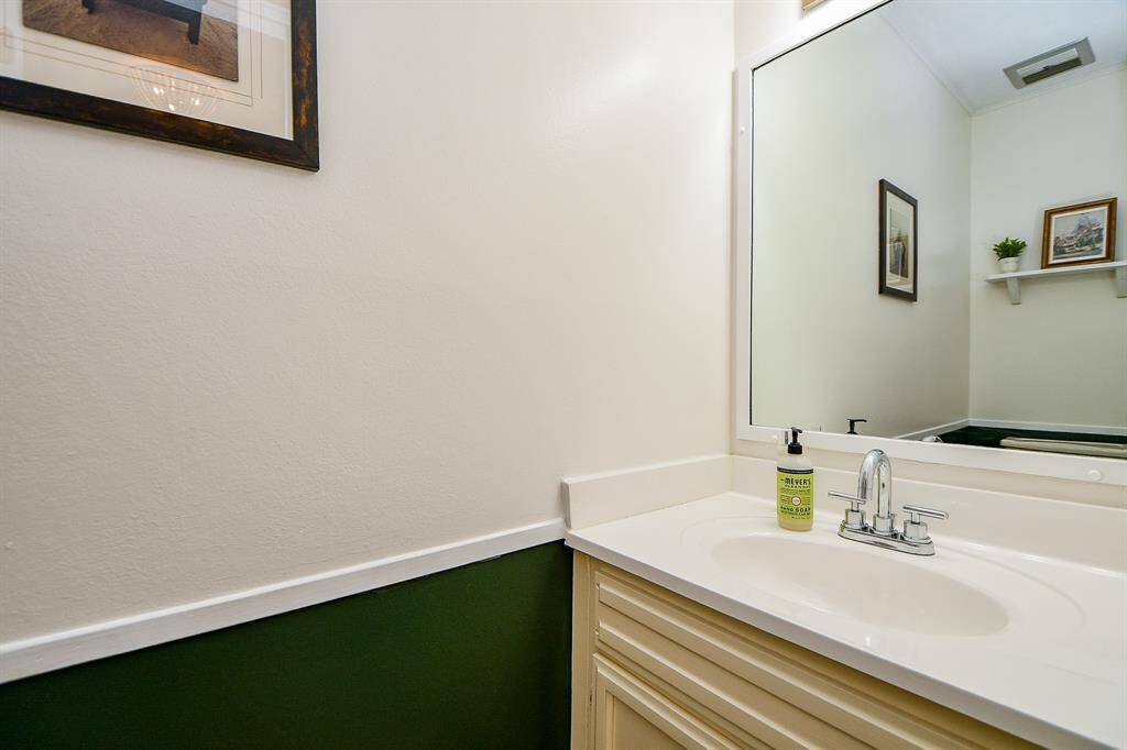 This bathroom features a clean, modern design with a white vanity, a large mirror, and simple decor. The walls are two-toned with a green lower half, adding a touch of color.