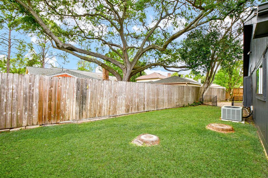 Spacious backyard with a well-maintained lawn, mature trees providing shade, and a wooden fence for privacy. Ideal for outdoor activities and entertaining.