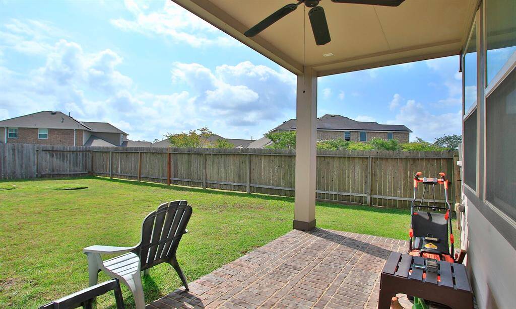Under the balcony is a covered patio.   Notice the brick floor and the ceiling fan.
