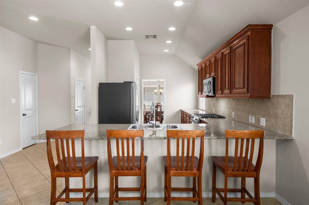Open to the living room, the spacious kitchen shines with granite countertops, stainless steel appliances, and ample prep space; ideal for everyday meals or entertaining guests with ease.