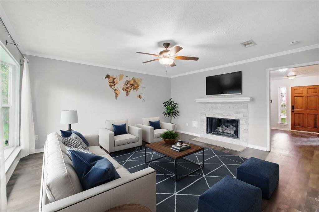 Spacious family room featuring a beautifully updated fireplace surround with mantle and gas logs—perfect for those colder, winter nights. This photo is virtually staged.