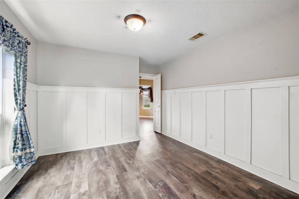 Gorgeous formal dining room with wainscoting detail and abundant natural light. Double doors lead to the kitchen - perfect for hosting family gatherings.