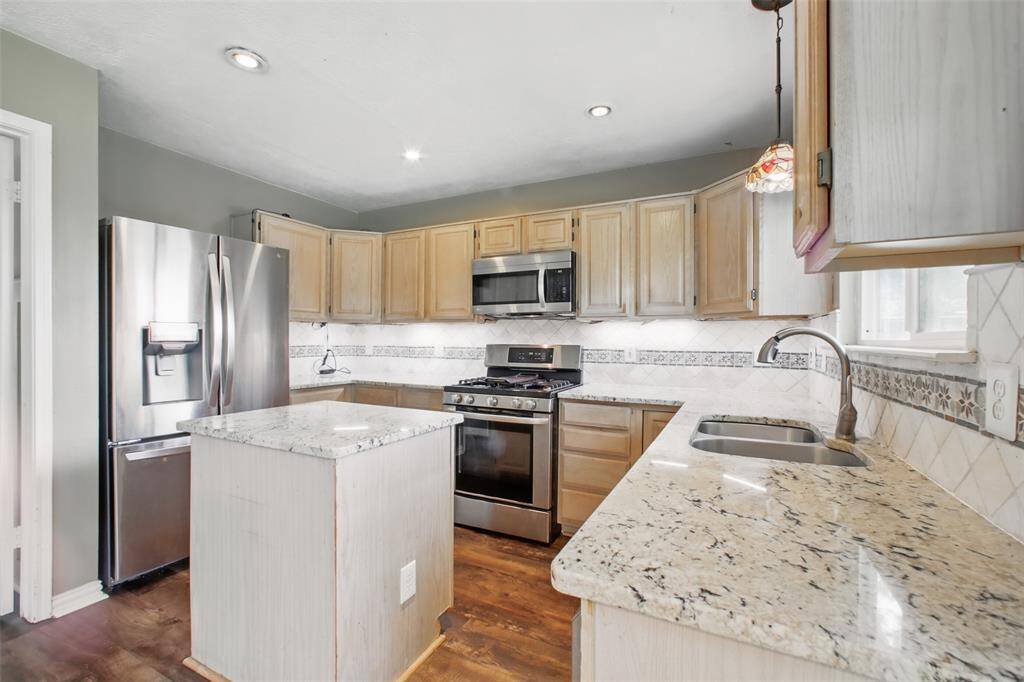 Modern kitchen offers granite countertops, gas range, stainless steel appliances, an island, and ample counter space.