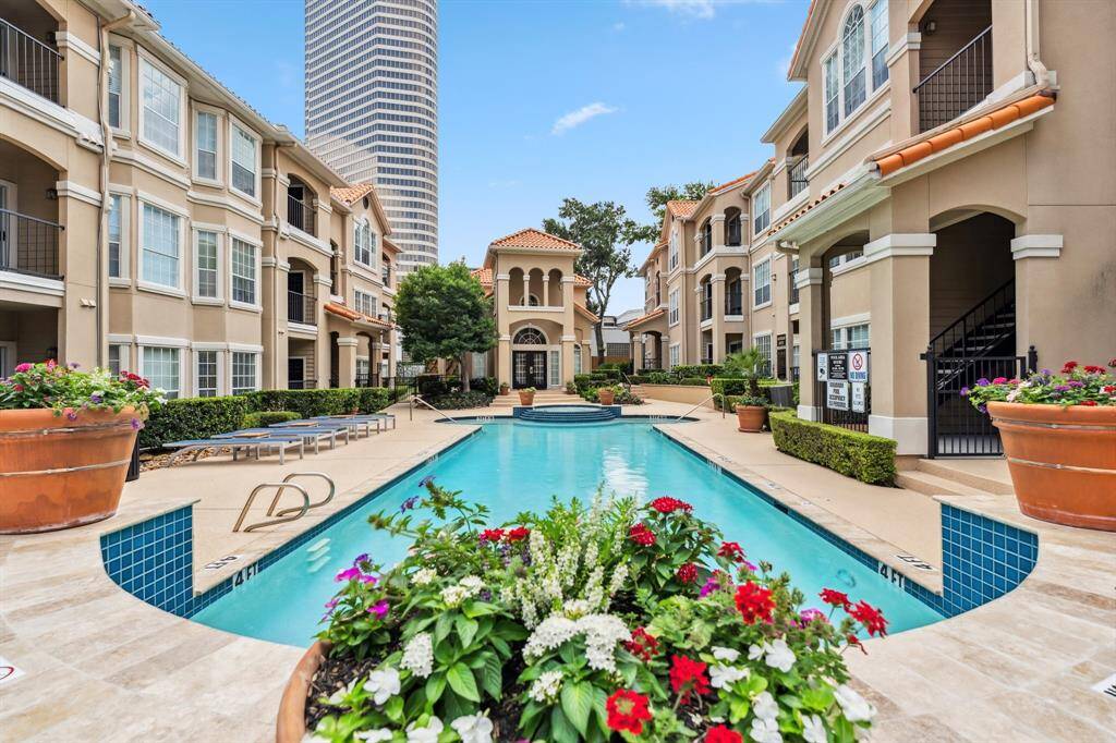 Resort-style pool at Reata at River Oaks with lush landscaping and view of the clubhouse. Residents enjoy grills, lounge seating, and beautifully maintained common areas in this private, gated Houston community.