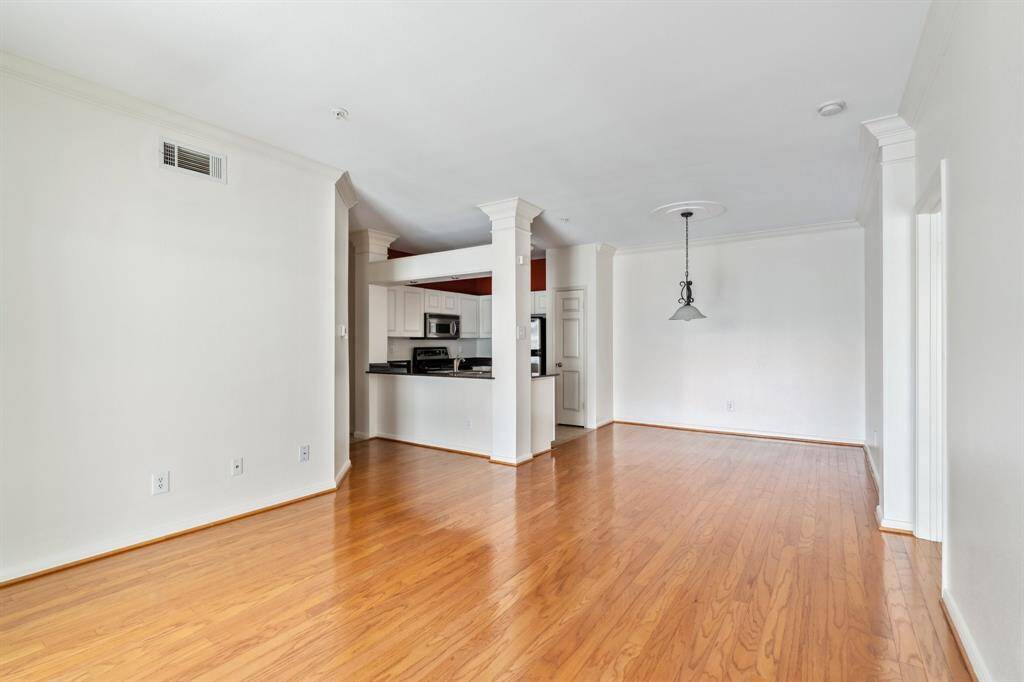 Spacious living room with wood flooring, ideal for entertaining. Open layout flows seamlessly into dining and kitchen areas.