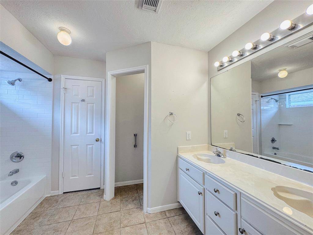Primary bedroom with bay windows, double sinks, tub/shower combo and large walk-in closet