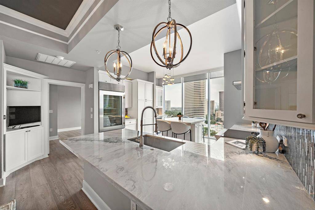 A marble-finished peninsula anchors this open-concept kitchen, complemented by sleek cabinetry and uninterrupted skyline views beyond.