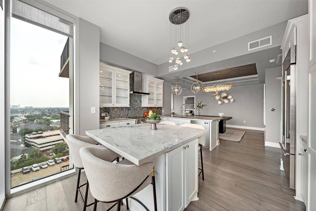 This expansive eat-in kitchen stretches toward the dining area, offering extended prep counters, layered lighting, and a bright, gallery-like ambiance.