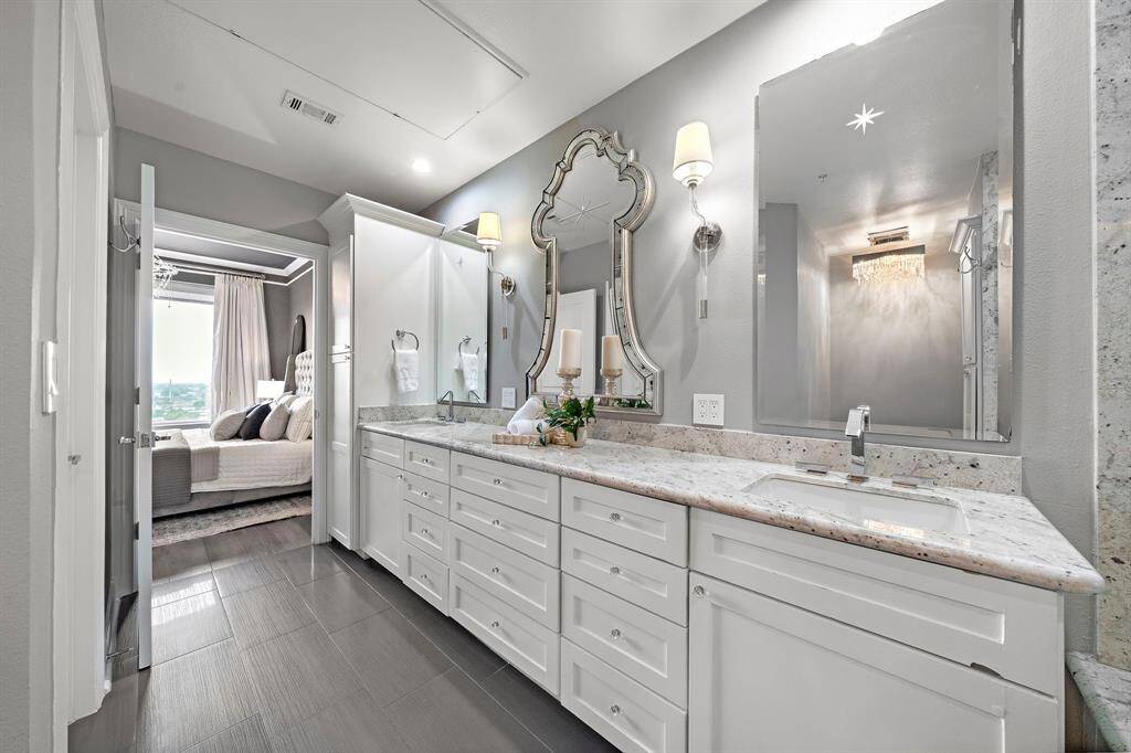 Just beyond the bedroom, the primary ensuite bath begins with a full-length double vanity topped in polished marble, paired with deep cabinetry for seamless storage.