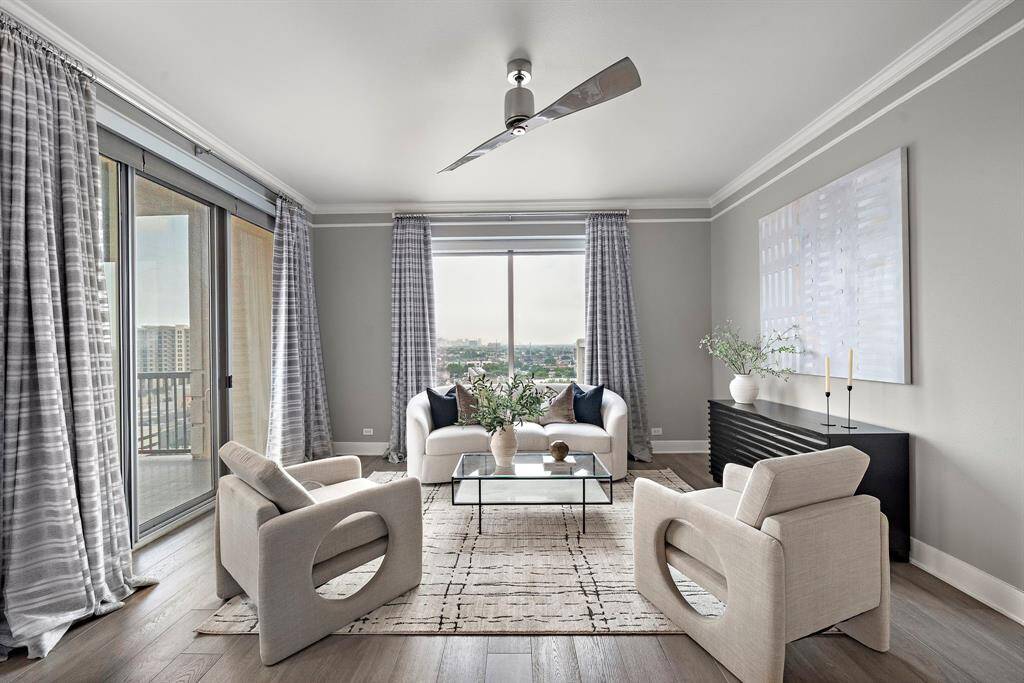 Floor-to-ceiling windows anchor the open living area with captivating views of Houston’s downtown skyline. The layout invites both relaxation and entertaining, framed by hardwood floors and a seamless connection to the adjacent kitchen and balcony.