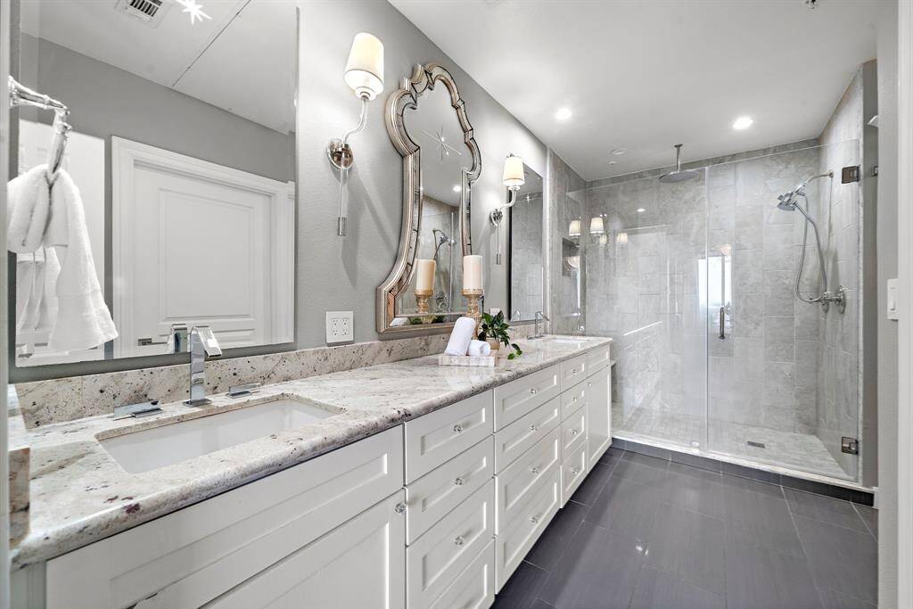 Set along its own wall, the frameless walk-in shower is finished with neutral tile and built-in shelving to keep essentials easily within reach.