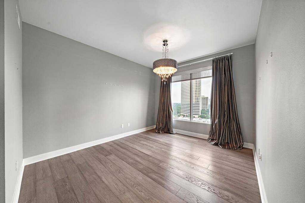 The secondary bedroom offers a private corner of the unit with wide-plank flooring, smooth walls, and a generous footprint suited for guests, a home office, or dual-use space.