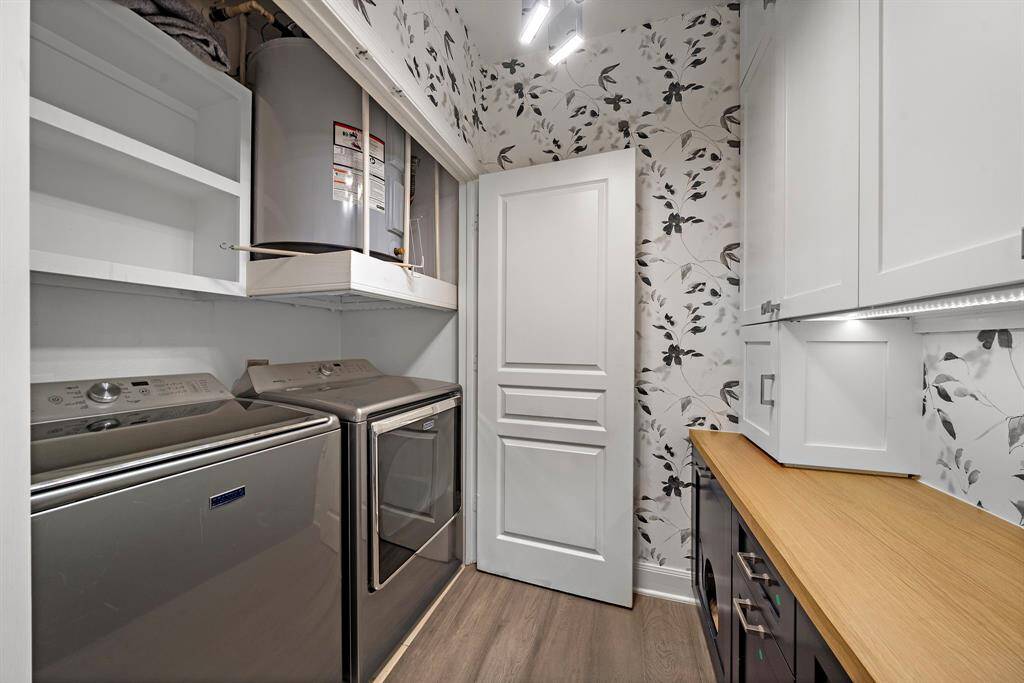 A built-in utility area features custom cabinetry, open shelving, and durable flooring—designed for everyday function with a refined finish.