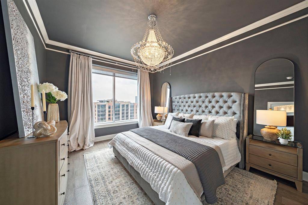 Serene and spacious, the primary bedroom features rich wall tones and oversized windows framing unobstructed skyline views. Elegant millwork and wide-plank hardwood flooring elevate the restful ambiance, while the layout offers generous room for a reading nook or seating area.
