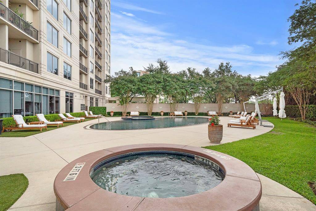 The adjacent spa sits slightly elevated from the pool deck, offering a more secluded setting bordered by soft turf and planters.