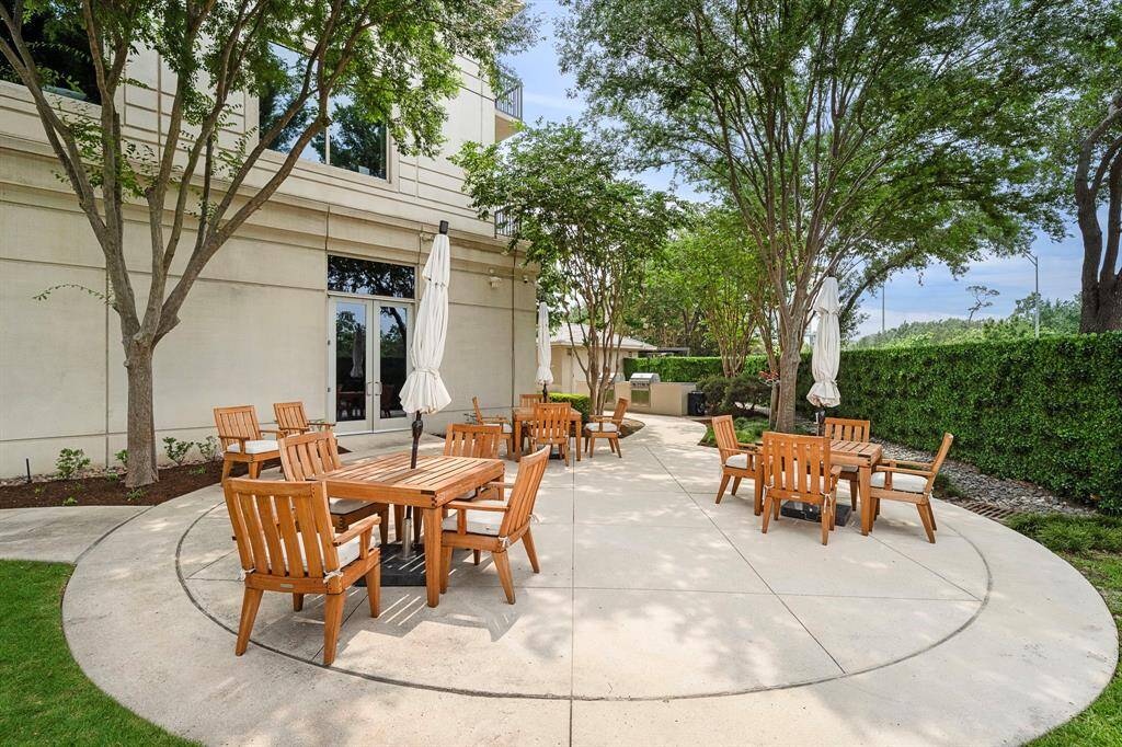 Beyond the pool, a serene patio area is shaded by mature trees and offers grouped seating for casual dining or open-air conversation.