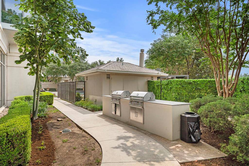 Two stainless steel grills are set along a landscaped path, giving residents a dedicated space to cook and gather outdoors.