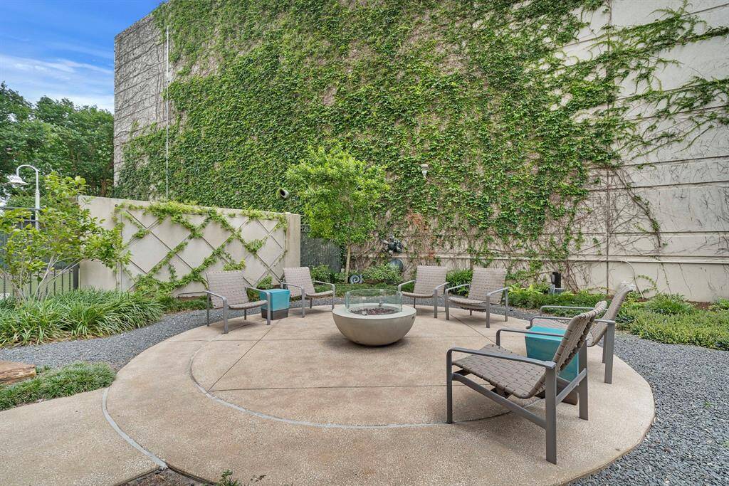 A circular fire pit anchors this garden-side lounge, surrounded by low-profile seating and climbing greenery for a relaxed evening setting.