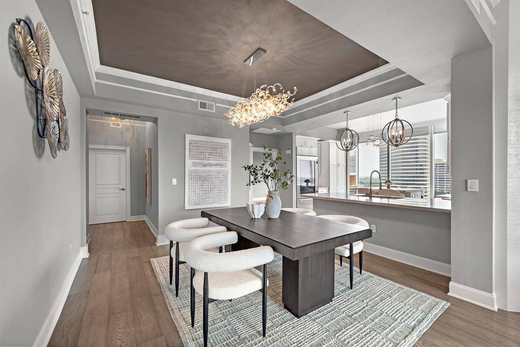 An open pass-through to the kitchen enhances the room’s flow, while soft gray tones and natural wood flooring create an effortlessly sophisticated setting.