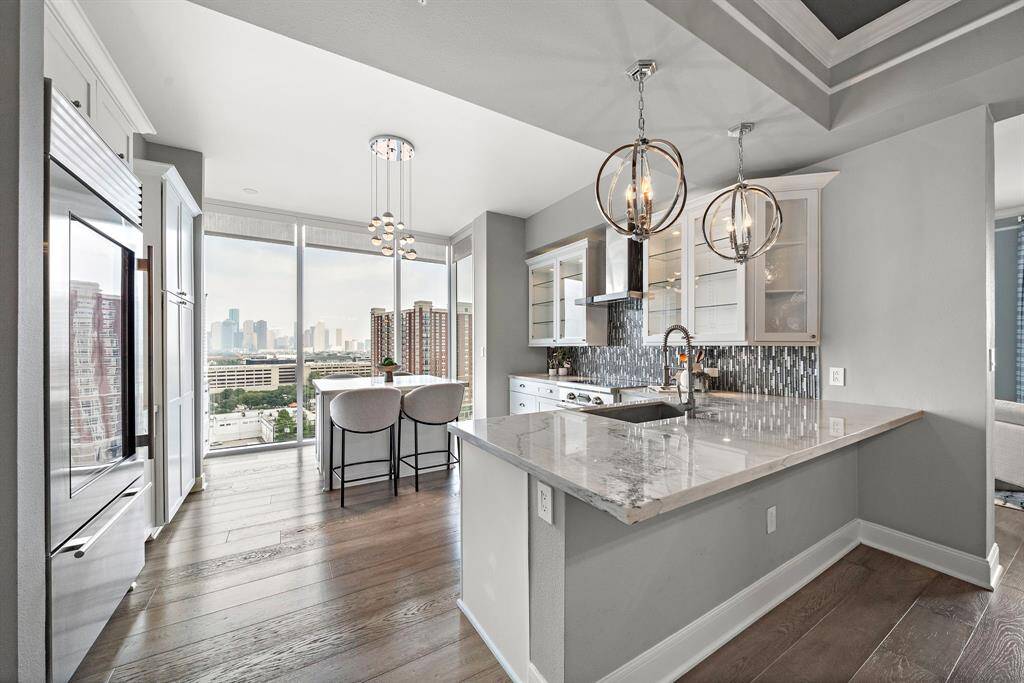 Positioned to capture natural light from multiple angles, the kitchen blends striking textures with seamless flow into the adjacent breakfast and gathering areas.