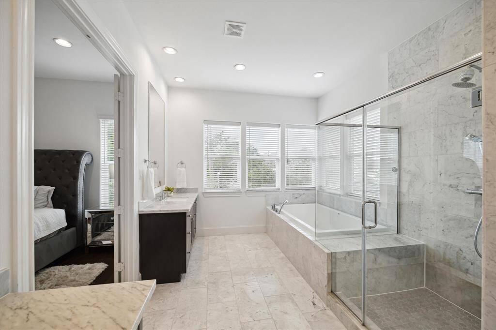Enjoy a relaxing soak in the deep tub set beneath a wall of windows, with a seamless transition to the expansive glass shower and spacious double vanity.