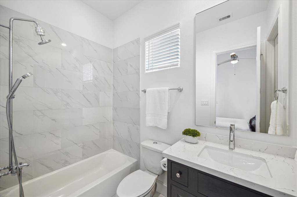 This stylish secondary bathroom features marble-look tile in the tub/shower combo, a sleek vanity with quartz countertop, and modern fixtures for a clean, elevated finish.