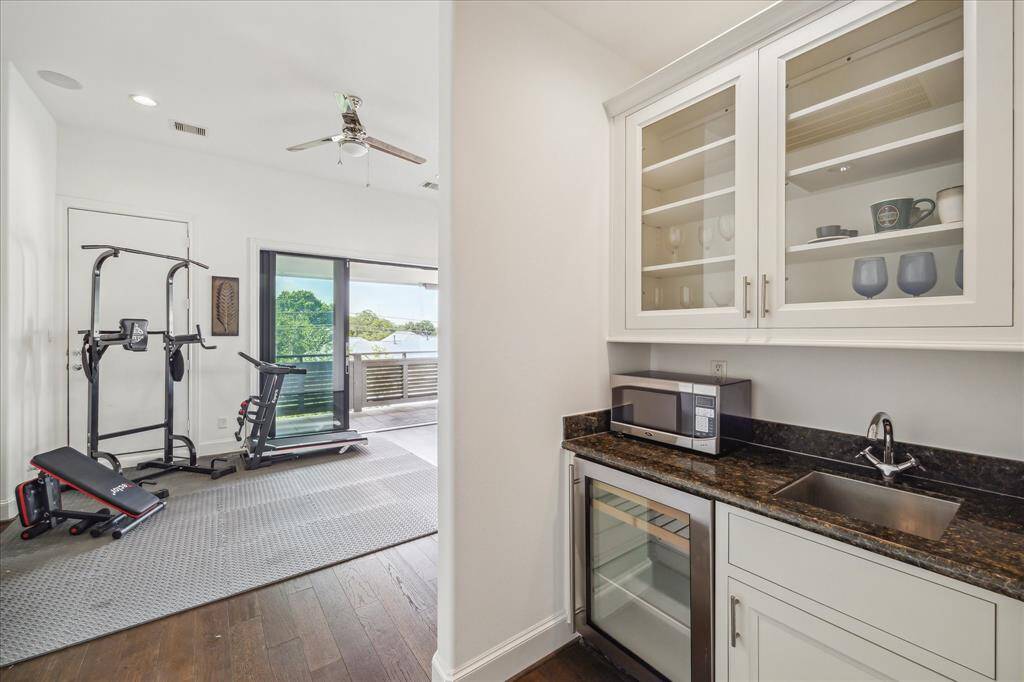 Entertain with ease from the third-floor game room, complete with a built-in wet bar featuring a wine fridge, sink, and upper display cabinetry with glass fronts—perfect for hosting or relaxing with a view.