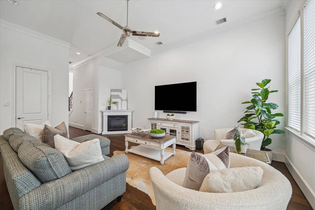 Crisp white walls and crown molding frame this elegant living room with easy access to a conveniently located half bath and the attached two-car garage—both just steps away through the nearby doors.