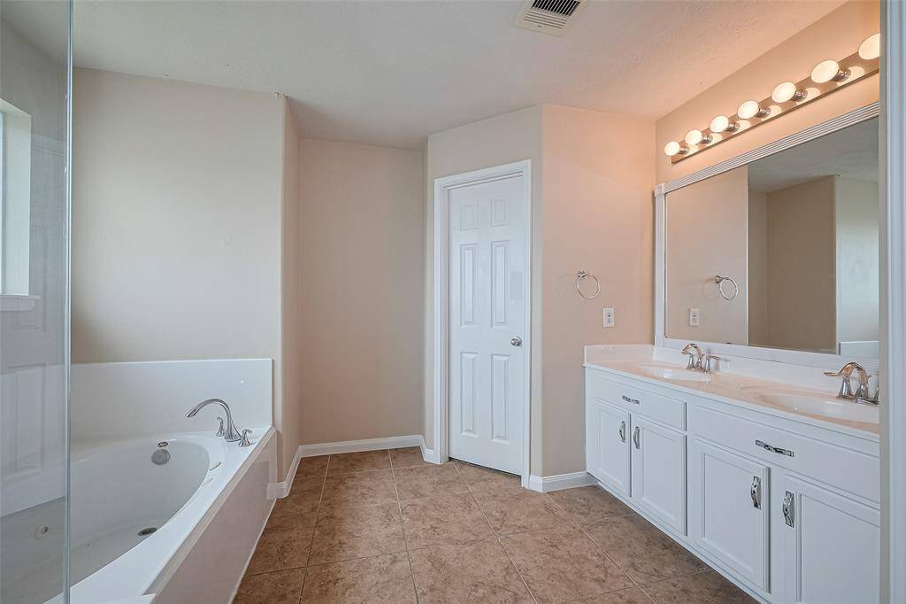 The primary bathroom features a sleek double vanity, offering ample space for morning routines and shared convenience.