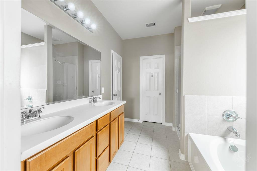 The primary bathroom is a serene oasis, designed with both functionality and elegance in mind. At its center are dual sinks, each set within a beautifully crafted vanity that offers ample counter space for personal care items. These vanities, with their sleek granite countertops, provide a touch of sophistication and practicality, ensuring that morning routines are both efficient and pleasurable.