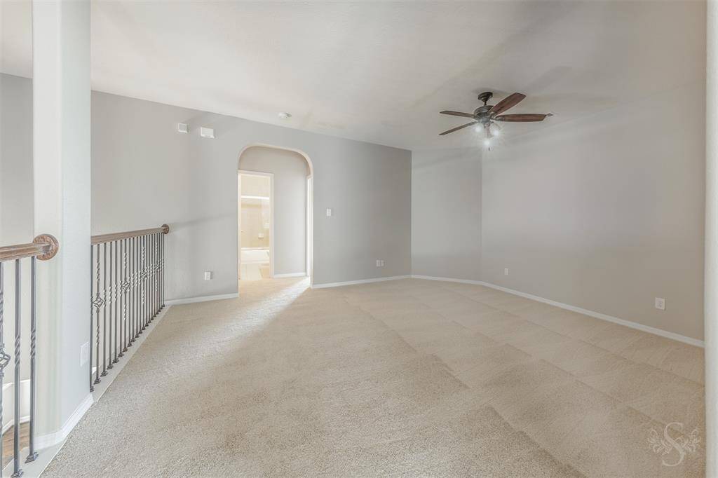 The hallway is softly illuminated by stylish lighting fixtures, guiding you towards the lively game room at the far end. This pathway is adorned with elegant decor and personal touches, such as family photos and artwork, adding character and warmth to the corridor.