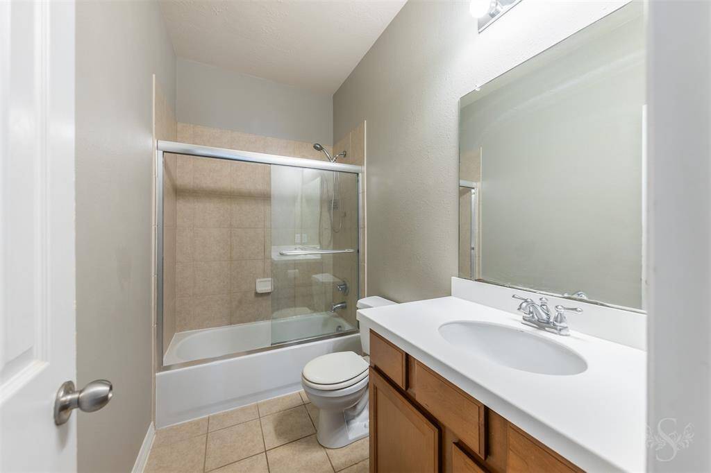 The bathroom features a combination shower and bathtub, offering flexibility for both quick showers and leisurely baths. The shower area is enclosed with a clear glass door, adding to the room's modern appeal while making maintenance a breeze.
