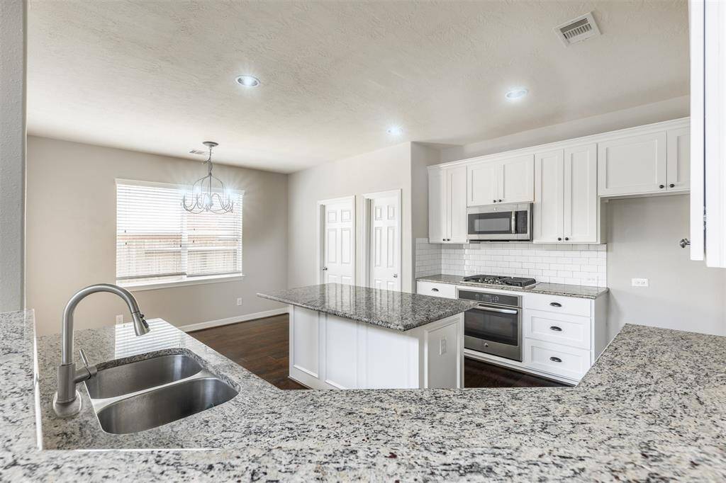 Imagine stepping into a beautifully remodeled kitchen adorned with custom-built white wood cabinets, bronze hardware, and modern granite countertops, all designed to inspire your culinary adventures.