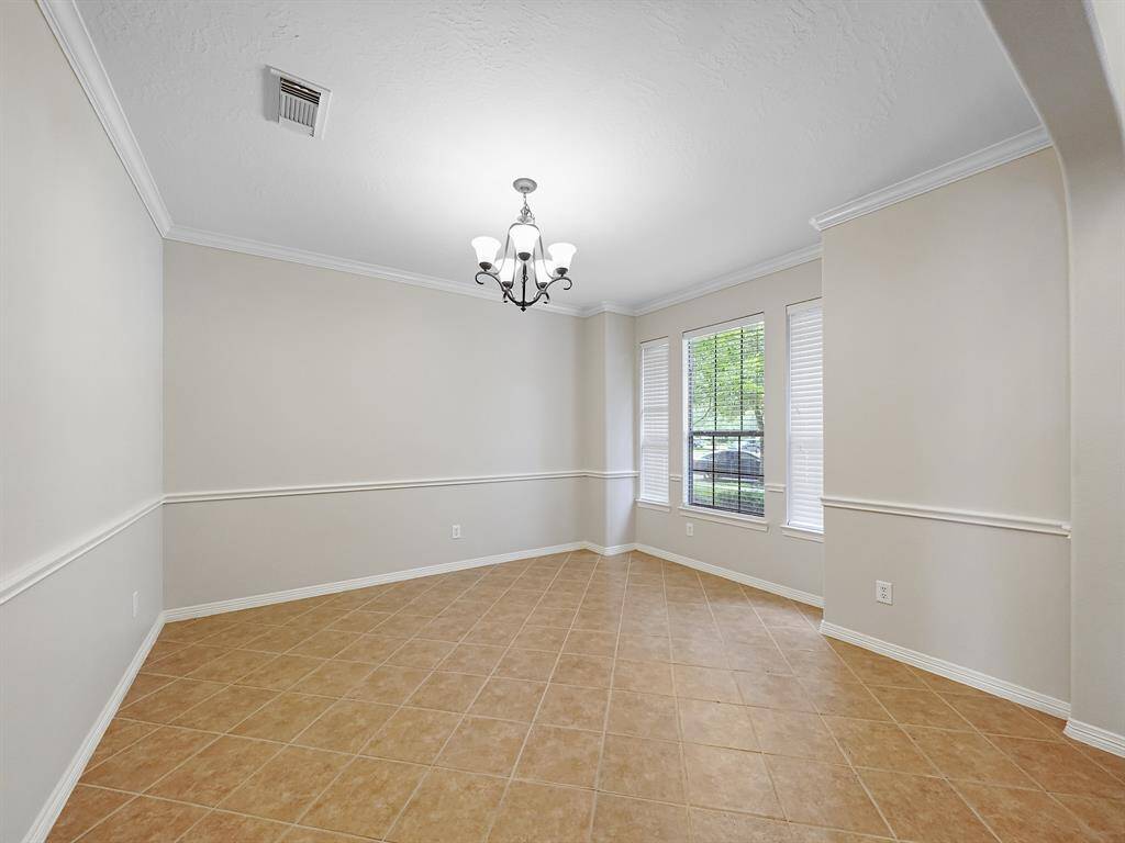 Step into elegance. The formal dining room, conveniently located off the entryway, exudes sophistication with its crown molding, a beautiful chandelier casting a warm glow, and a large window filling the space with natural light.