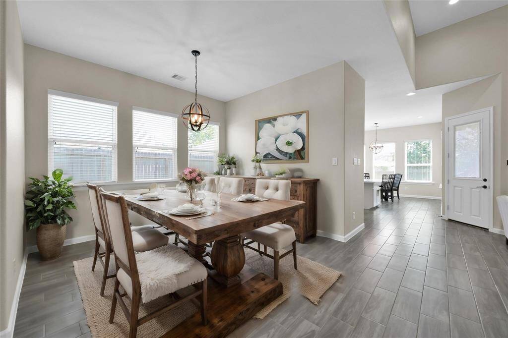 Elegant formal dining room with large windows and space to host family gatherings. Disclaimer: This image has been virtually staged to illustrate the property's potential. Furnishings, décor, and enhancements are for visual purposes only and may not reflect actual scale or existing conditions.