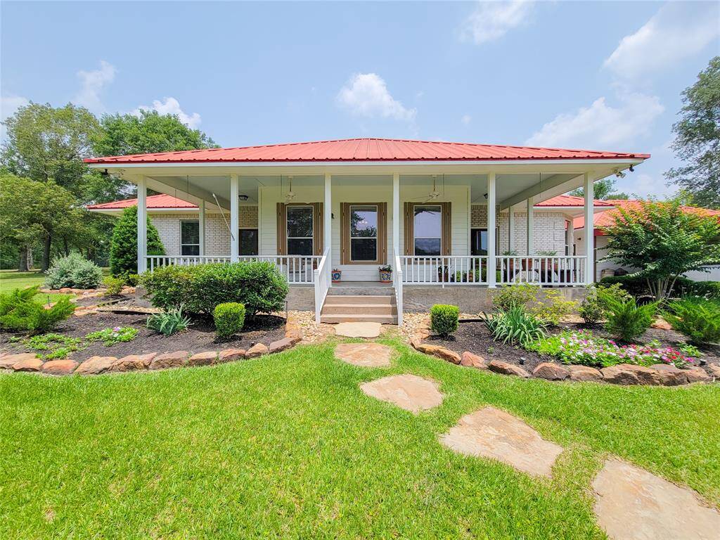 Charming single-story home and a spacious wrap around front porch. Surrounded by lush landscaping, it features a stone path leading to the entrance. Ideal for enjoying outdoor views and relaxing in a serene setting.