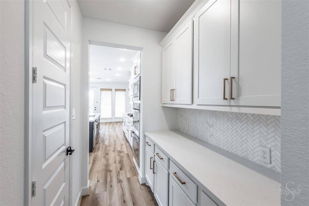 Extended countertop space and abundant cabinetry in the butler’s pantry provide lots of added storage. The matching herringbone backsplash continues the kitchen’s cohesive designer feel, while the layout is perfect for entertaining and serving meals with ease.