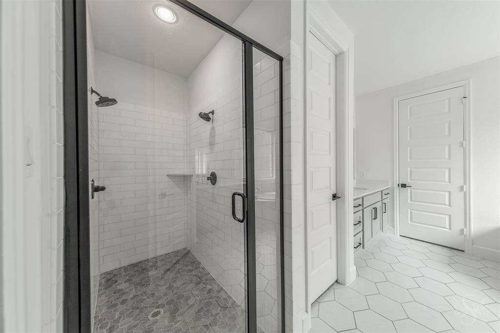 An enclosed glass shower with dual showerheads and subway tile surround offers a sleek, upscale experience. The clean lines and timeless design make this a truly rejuvenating space.