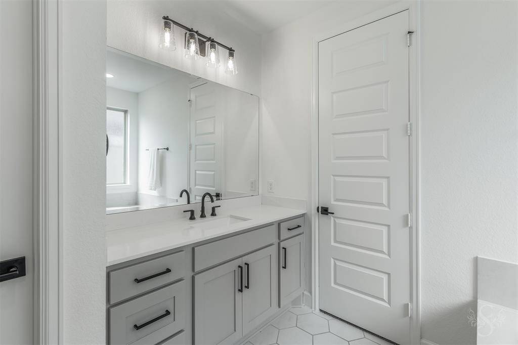 Dual vanities with quartz countertops and matte black fixtures combine style and function. Ample storage and designer lighting enhance the serene, polished aesthetic.