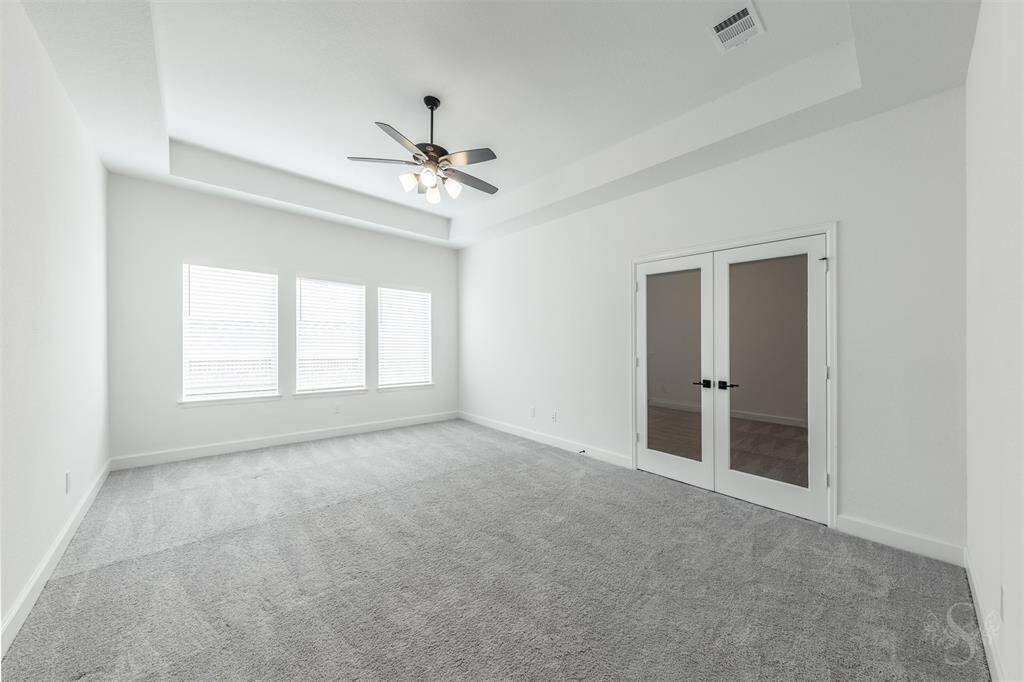 This spacious game room is a versatile retreat with plenty of room for a pool table, entertaining, relaxing, or setting up a play space. Tray ceilings and natural light from three large windows add a bright, open feel to the space.